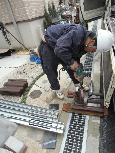 瓦へ支柱貫通用の穴あけ作業